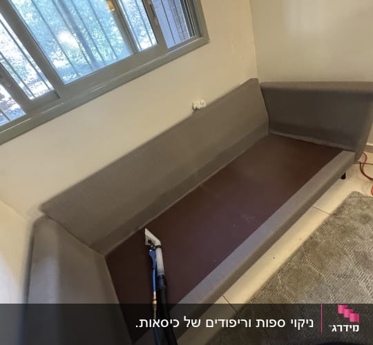 ספה עם מכשיר ניקוי ליד חלון